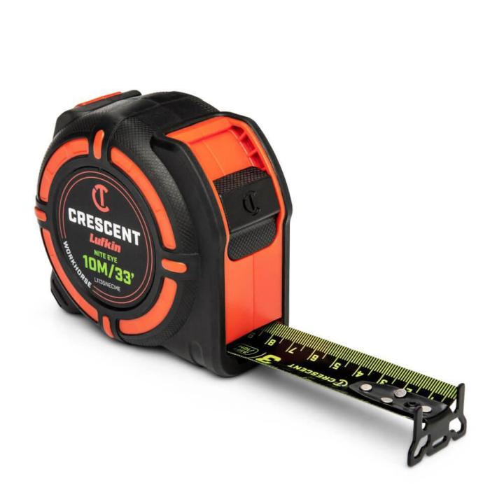 Crescent  1-1/4 x 8m/26' WORKHORSE NITE EYE Tape Measure  sitting on an angle with the blade end hook and blade lock facing the lower right corner with the blade extended 3 inches on a white background